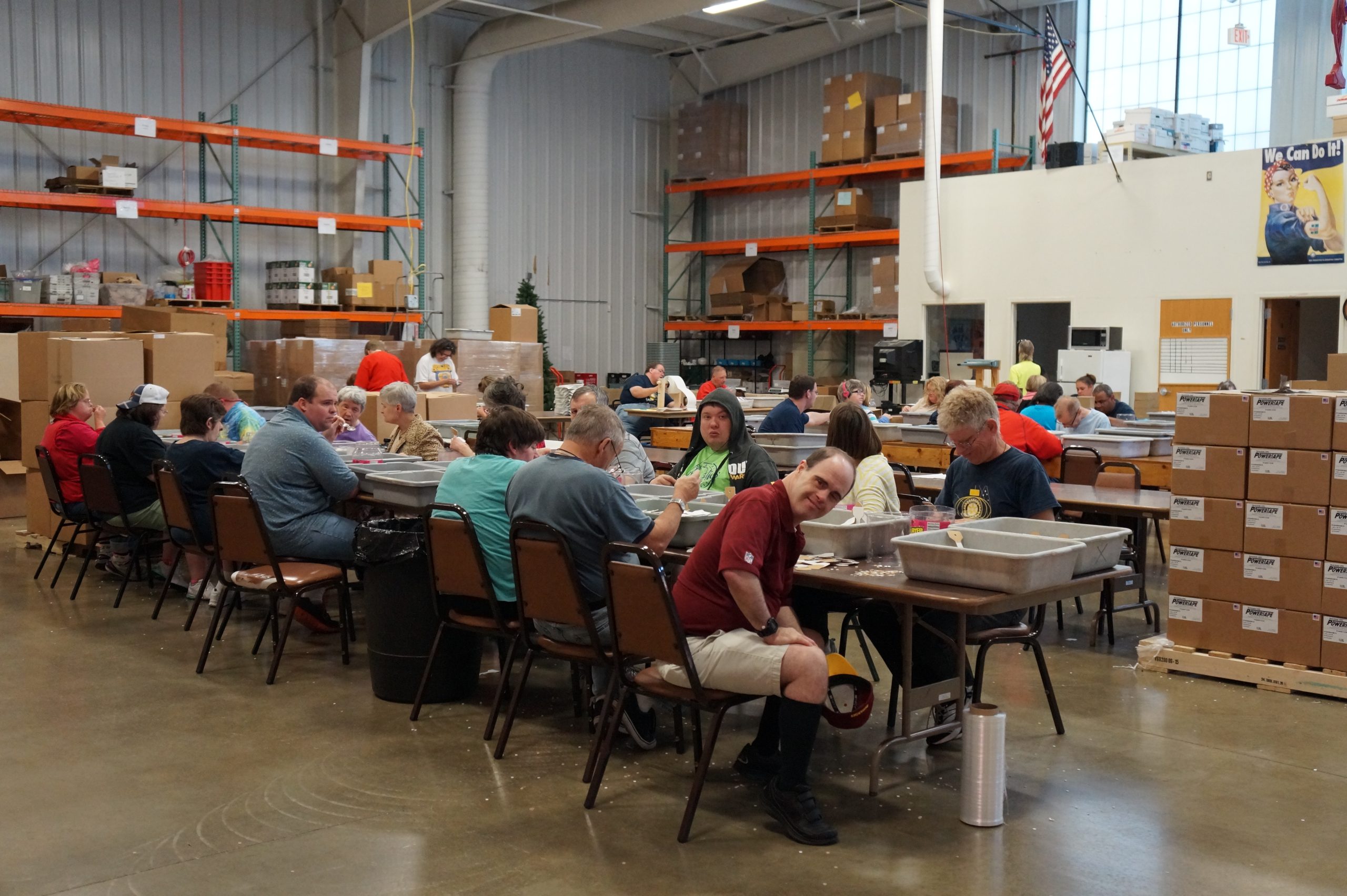 Group in warehouse workshop sitting at table.