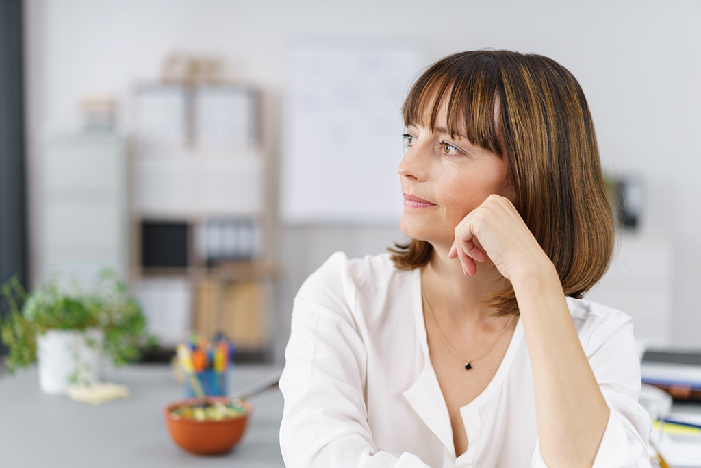 Middle-aged woman in a kitchen looking off into the distance.